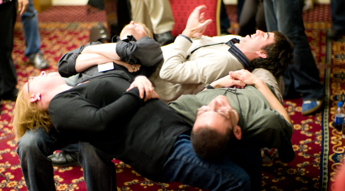 Four people using each others as support form a small spiral.